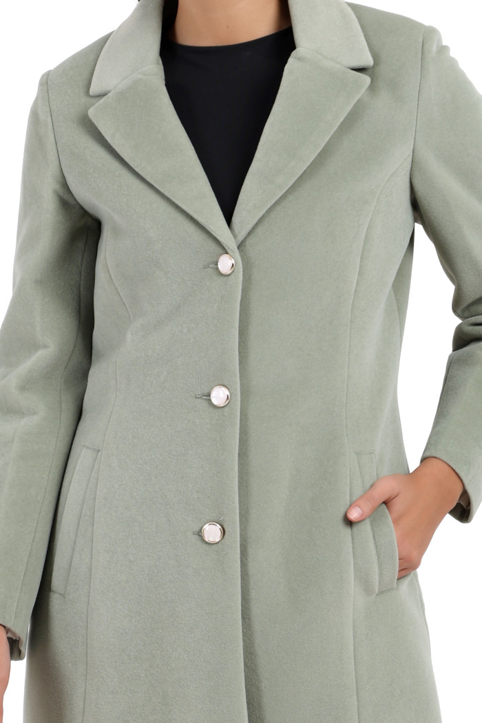 A woman in a cropped image is wearing Coatsnmore’s rust Semi-Long Velvet coat with a lapel collar, button closure and side pockets.